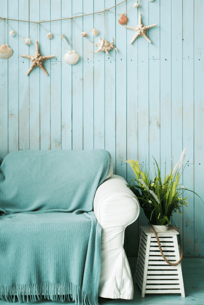 Coastal decor with blue shiplap and seashells on wall 