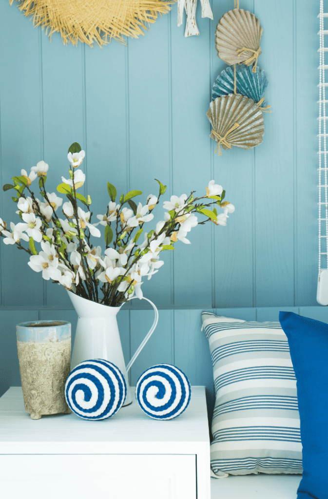 coastal decor with blue pillows and plants in white vase.